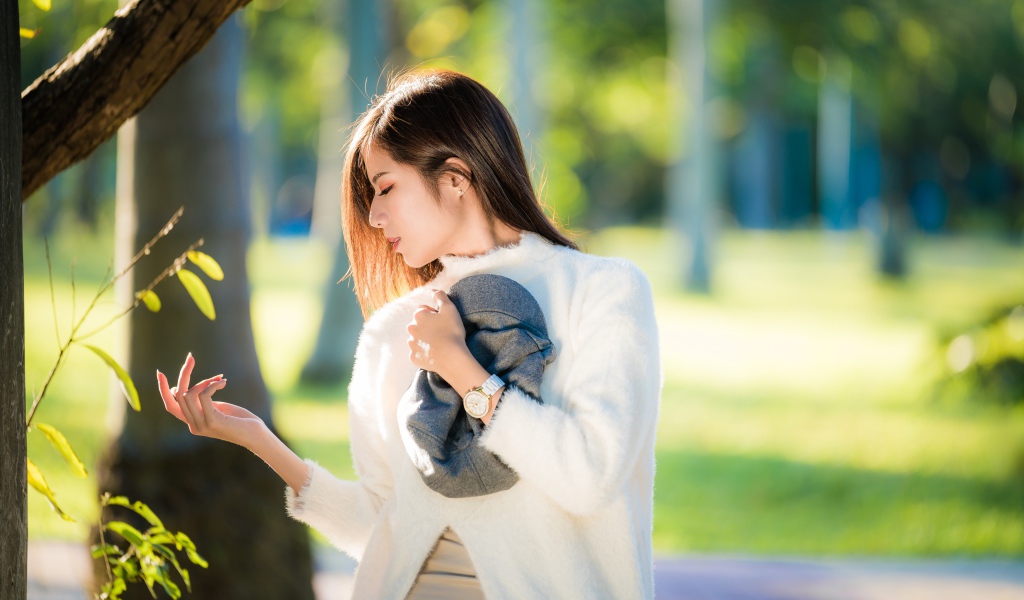 Красивая азиатка в белой кофте в солнечном парке