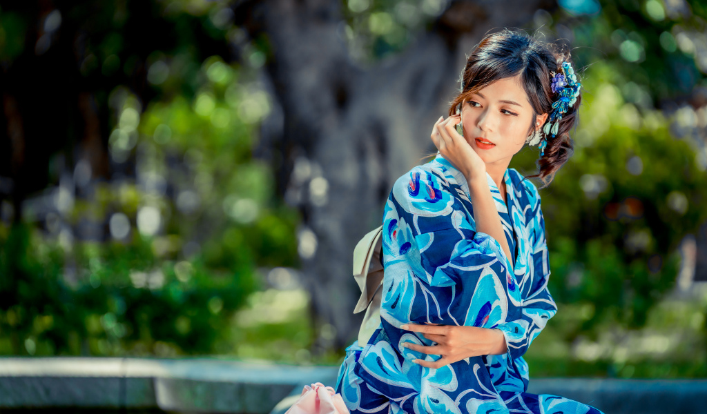 Красивая азиатка в разноцветном кимоно в парке