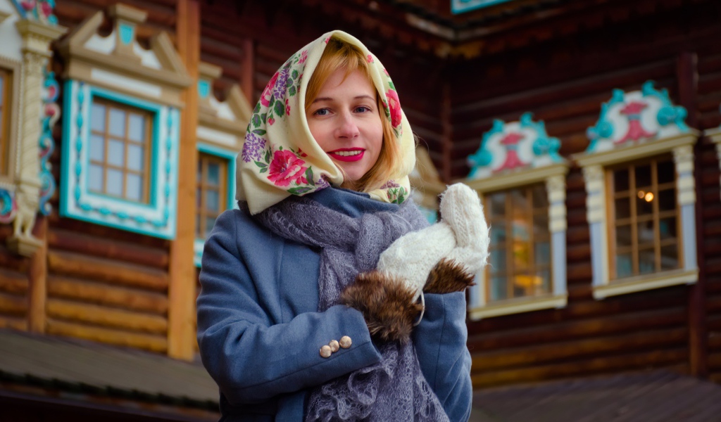 Красивая русская женщина в платке стоит у дома