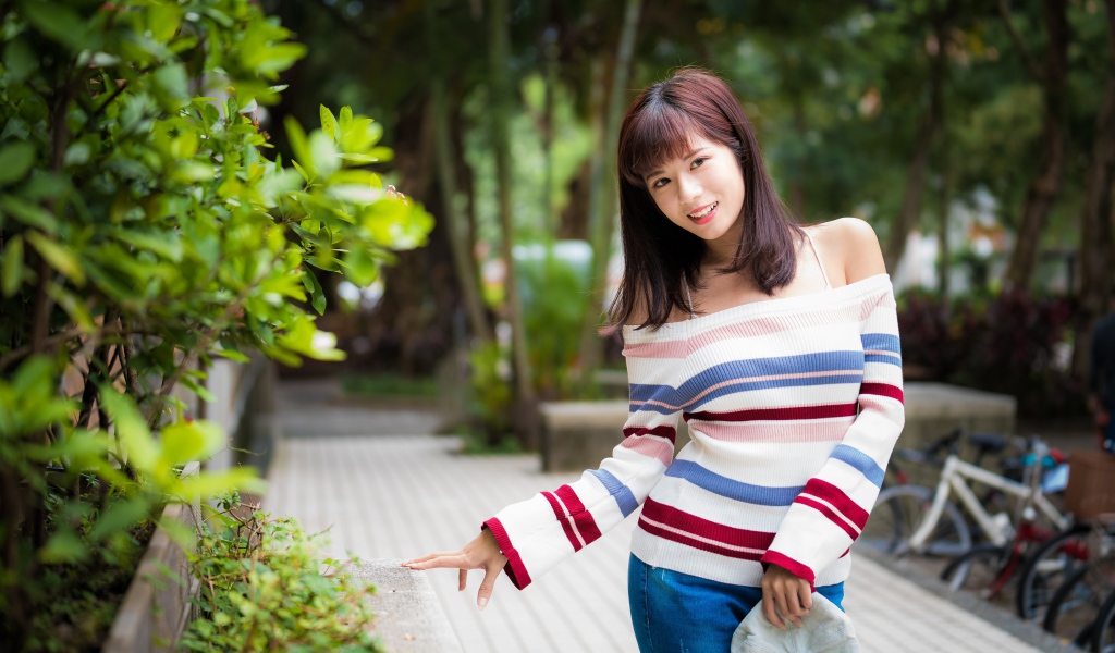 Красивая азиатка в полосатом свитере в парке