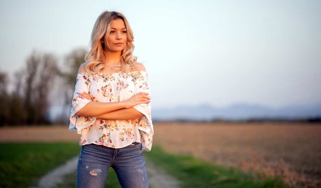 Красивая девушка блондинка в джинсах в поле