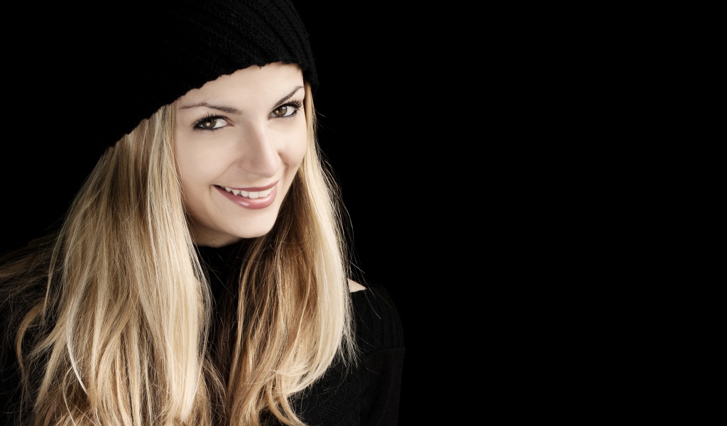 Красивая блондинка в шапке на черном фоне