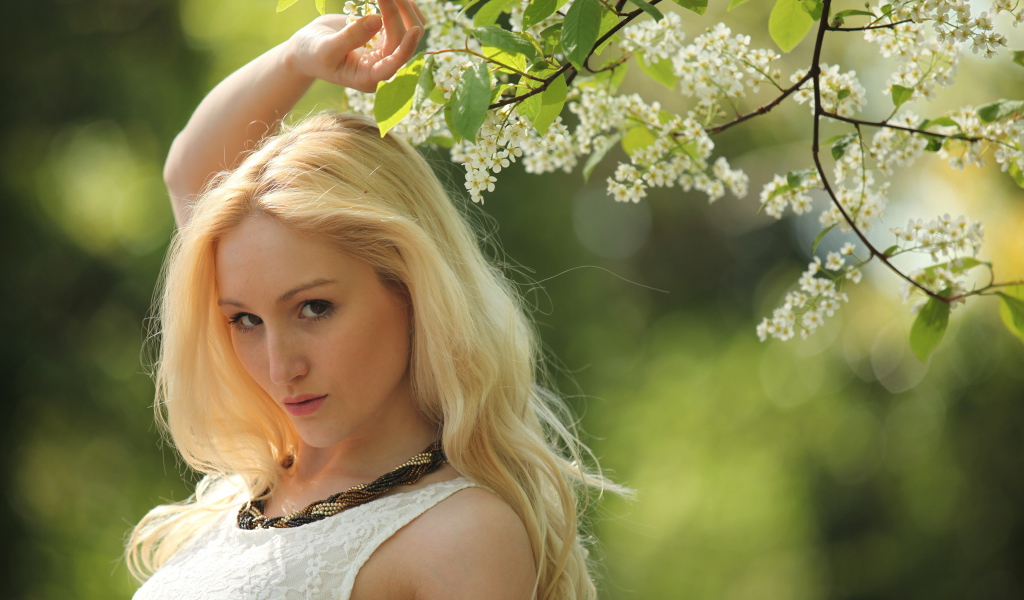 Красивая блондинка у ветки с белыми цветами
