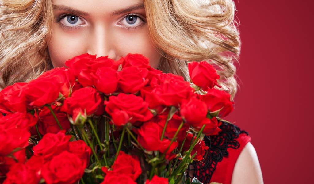 Красивая голубоглазая блондинка с букетом красных роз 