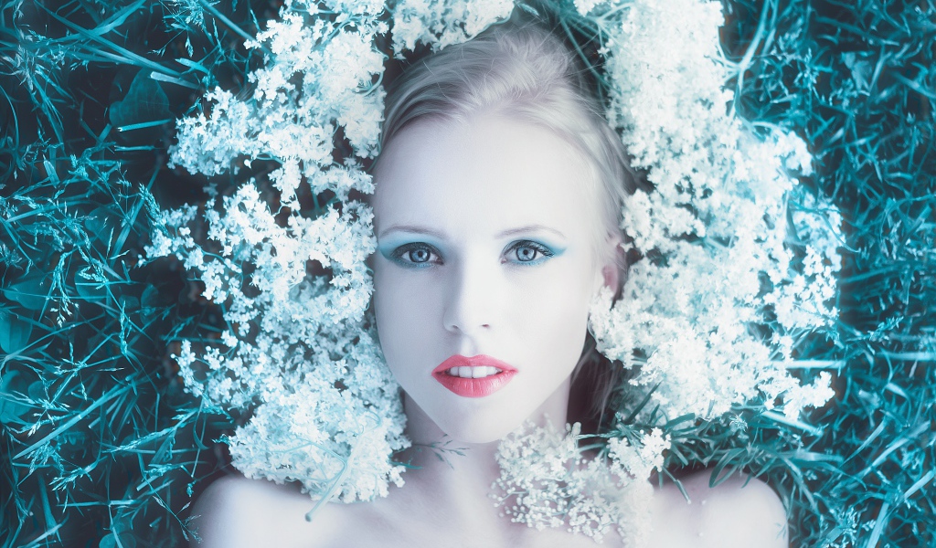 Красивая голубоглазая девушка на траве с белыми цветами