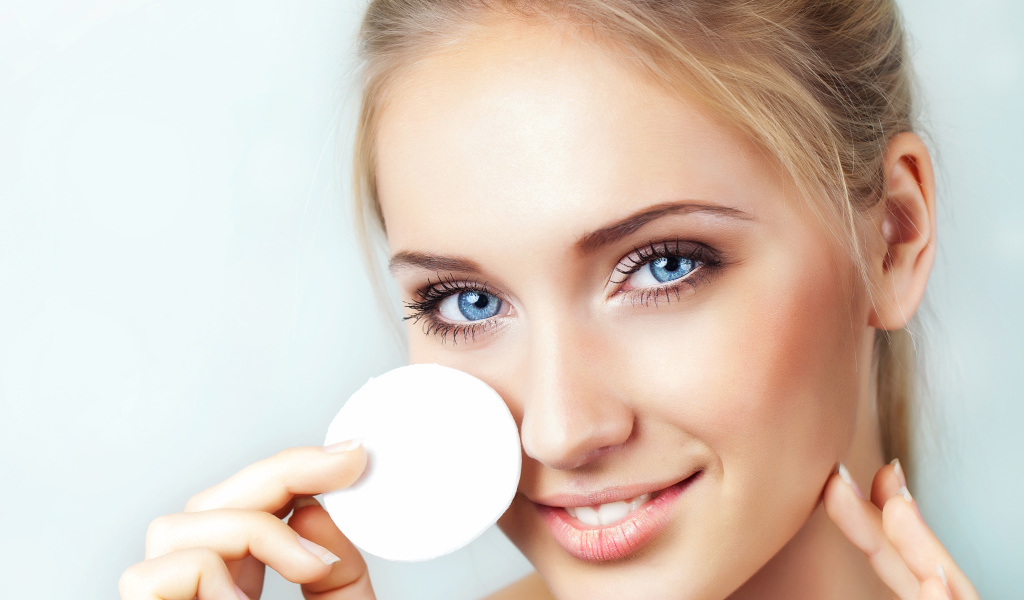Красивая голубоглазая девушка с ватным диском в руке 