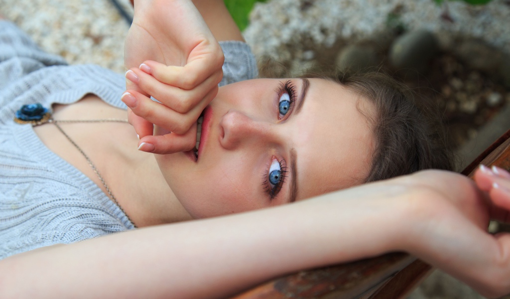 Красивая голубоглазая девушка с рукой у рта