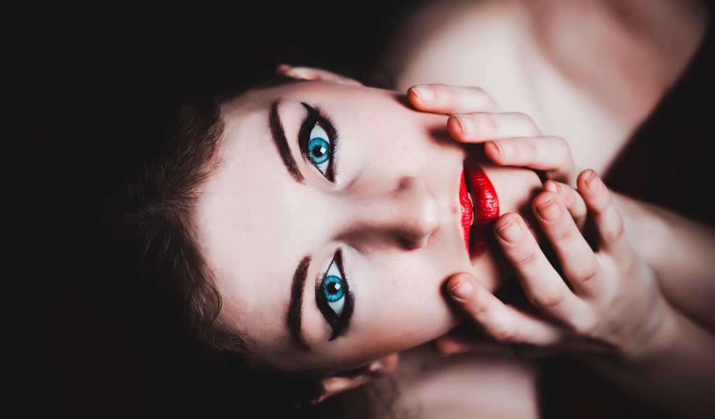 Красивая голубоглазая девушка с красными губами смотрит вверх 