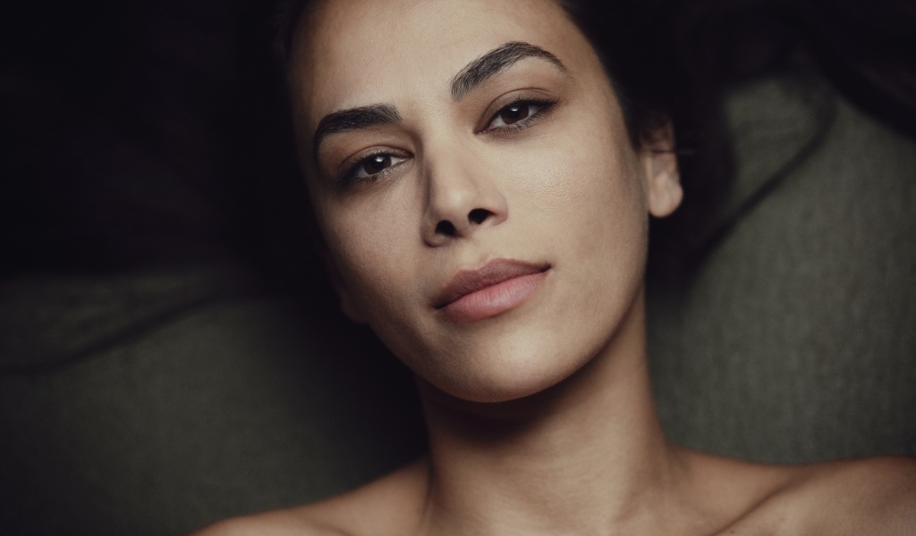 Красивая кареглазая девушка лежит на диване 