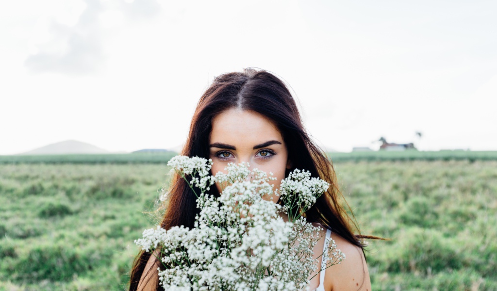 Красивая кареглазая девушка с букетом белых полевых цветов 