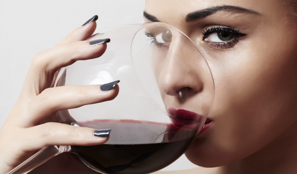 Красивая девушка пьет вино из бокала 