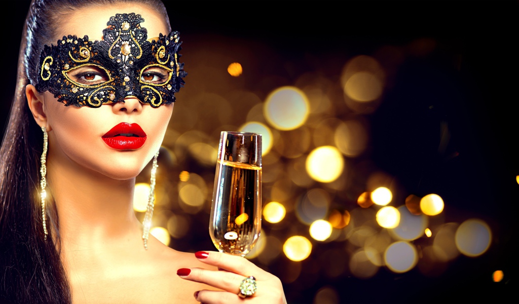 Красивая девушка в черной маске с бокалом шампанского