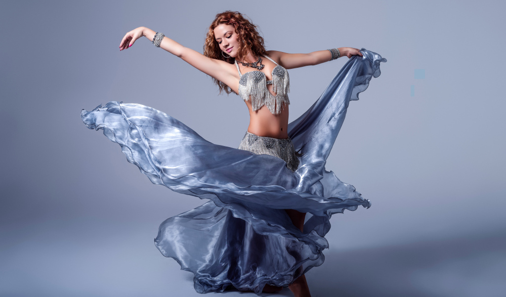 Красивая девушка в платье для танцев на сером фоне