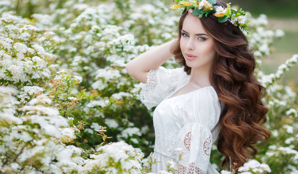Красивая девушка в платье у куста с белыми цветами