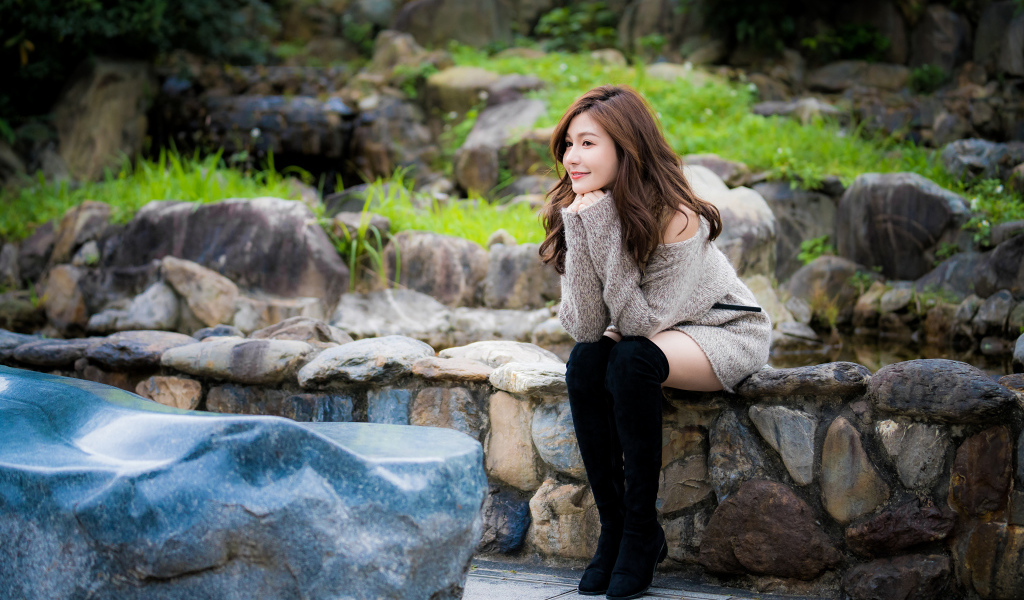 Красивая девушка в кофте сидит у пруда