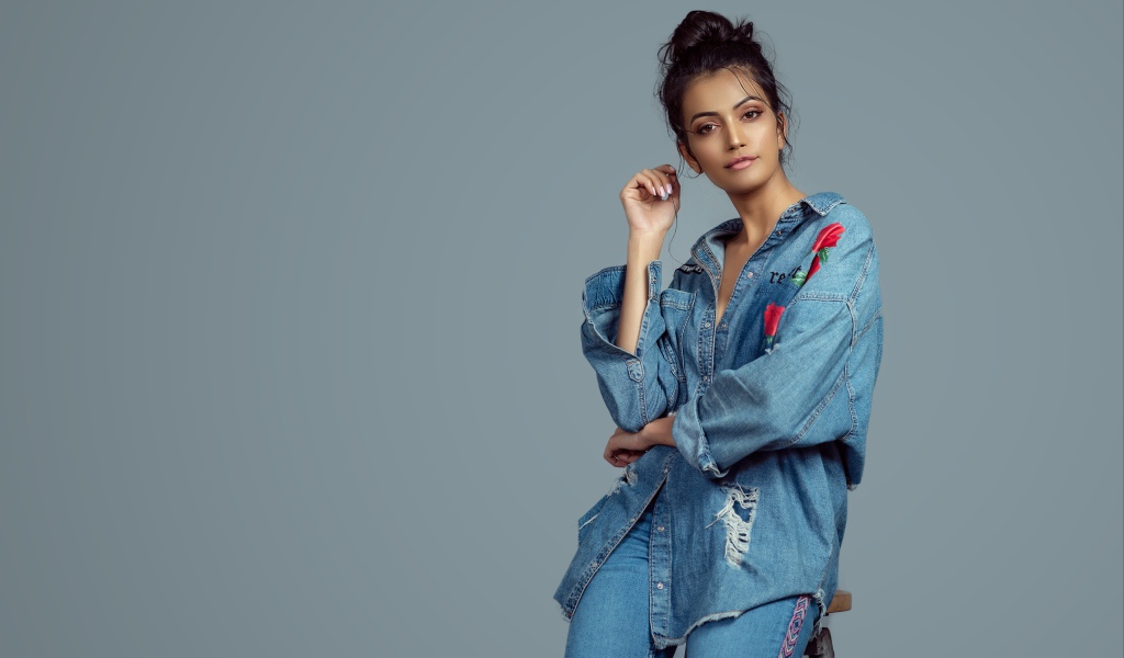 Красивая девушка в джинсовом костюме на сером фоне