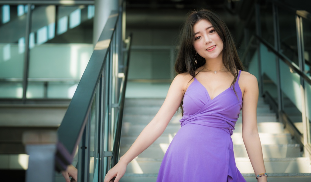 Beautiful girl in a lilac dress stands on the steps