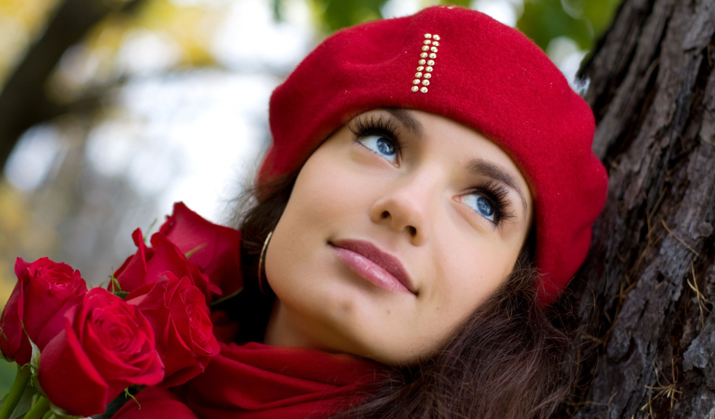 Красивая девушка в красном берете с букетом роз у дерева