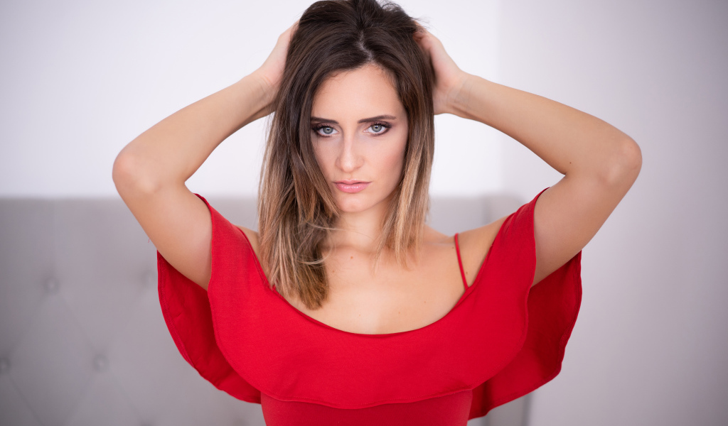 Beautiful girl in a red dress with hands in hair