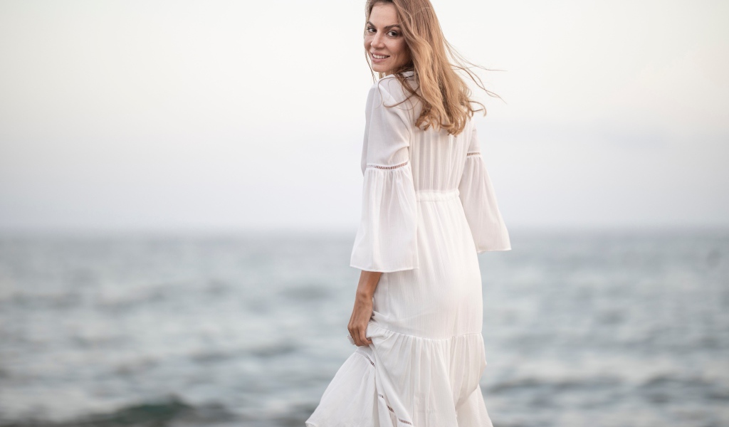 Красивая девушка в белом платье у моря