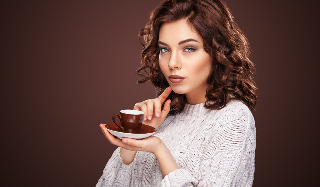 Красивая девушка в белом свитере с чашкой кофе