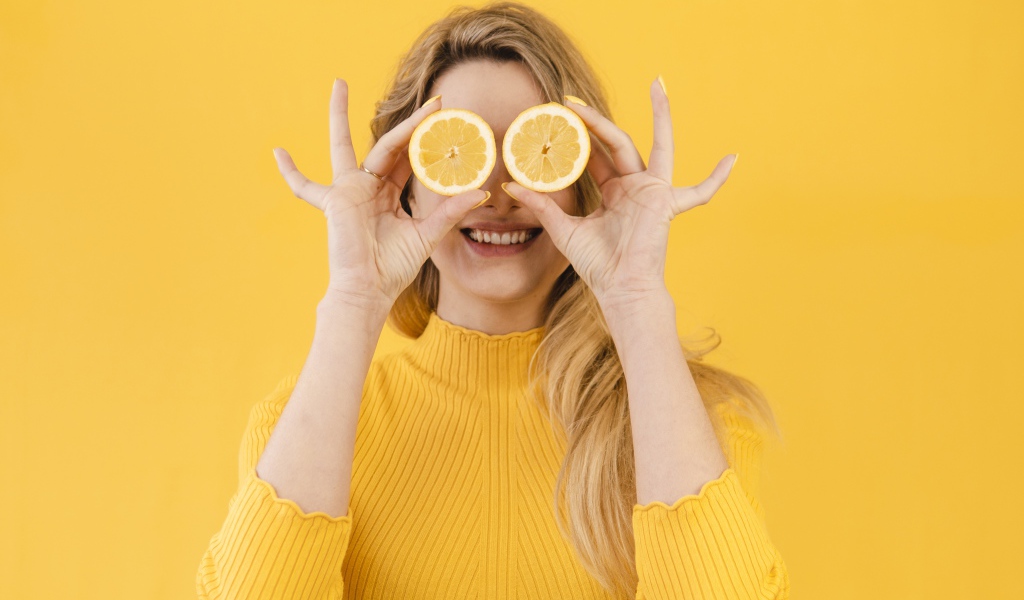 Красивая девушка в желтом свитере с лимоном