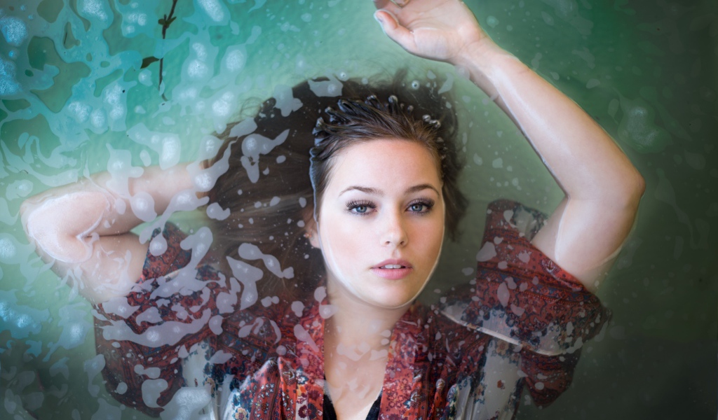 Красивая девушка лежит в одежде в воде 