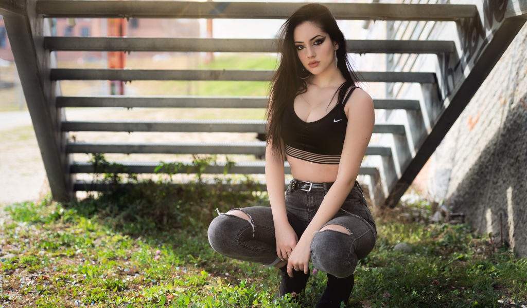 Красивая девушка сидит под лестницей 