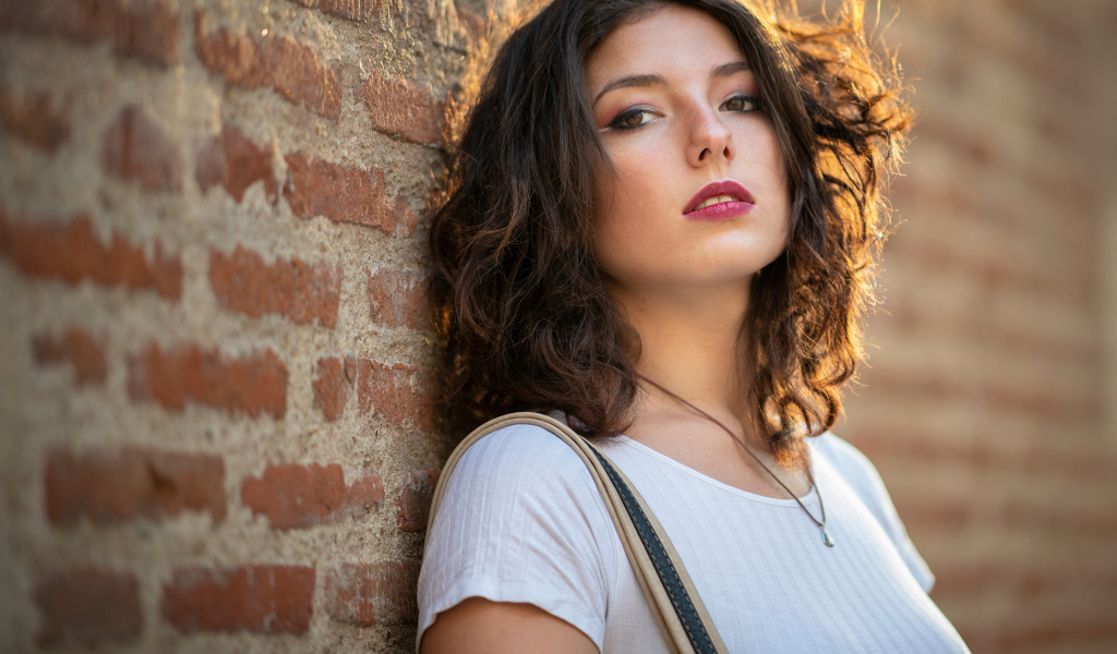 Красивая девушка стоит у стены 
