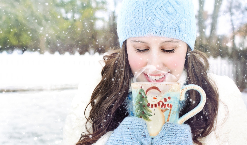 Красивая девушка с чашкой горячего кофе на улице зимой