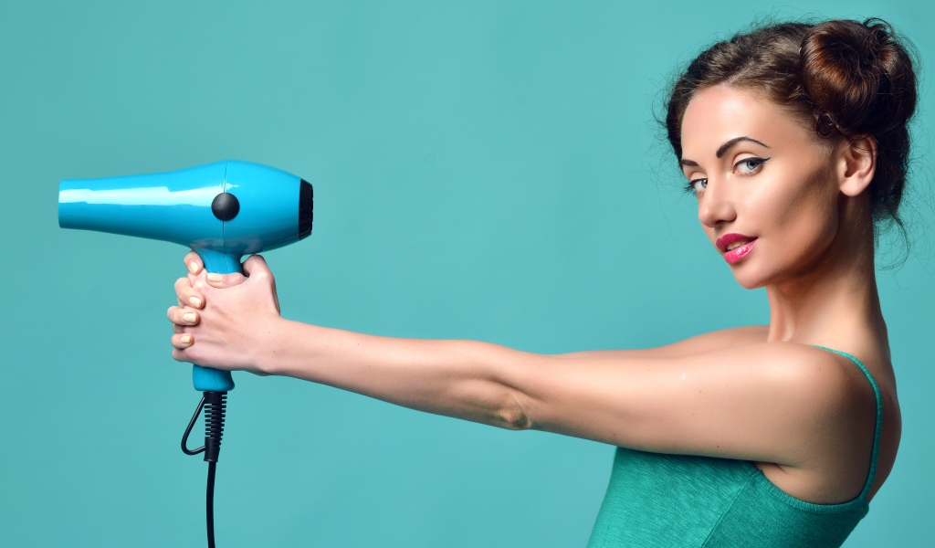 Beautiful girl with a hairdryer in hands on a blue background