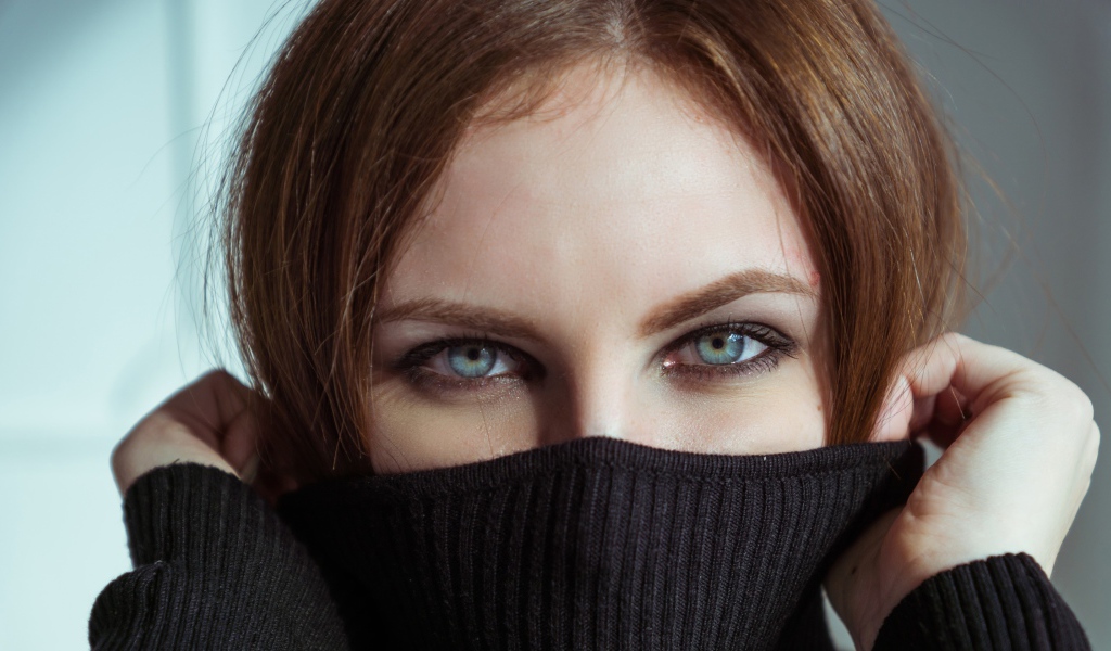 Красивая девушка с голубыми глазами закрыла лицо свитером 