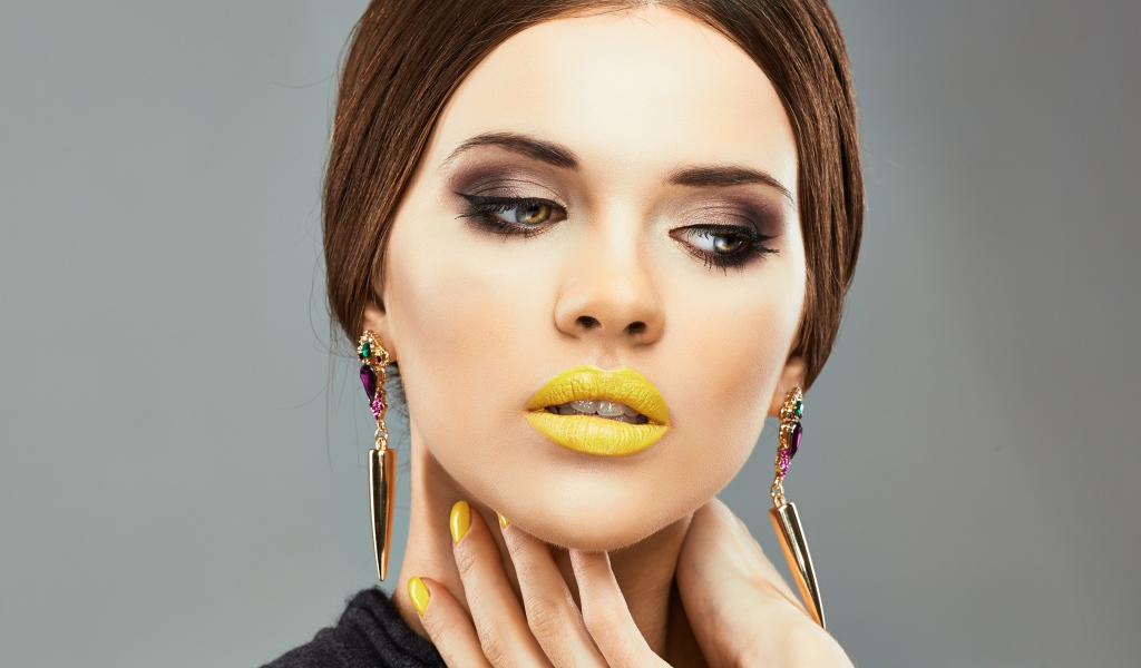 Красивая девушка с дорогими серьгами в ушах на сером фоне