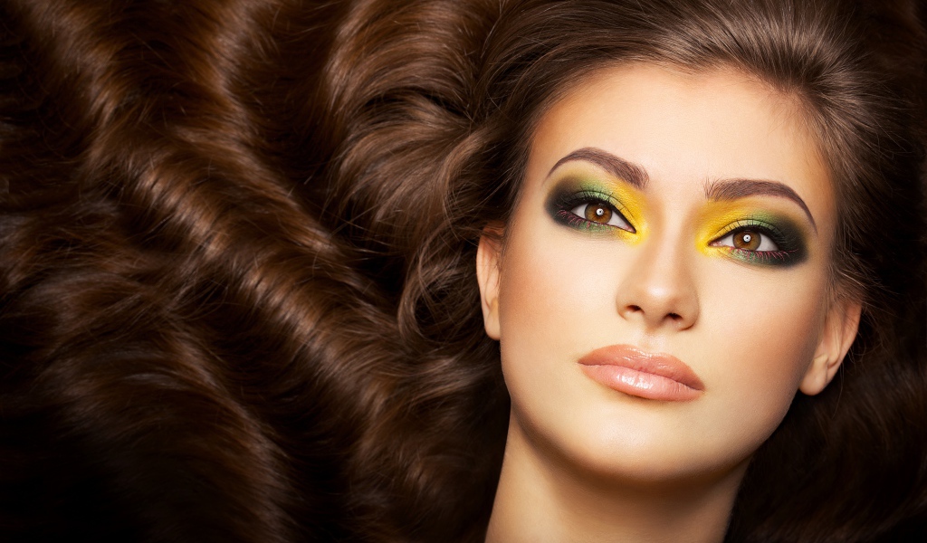 Красивая длинноволосая девушка с ярким макияжем на глазах 