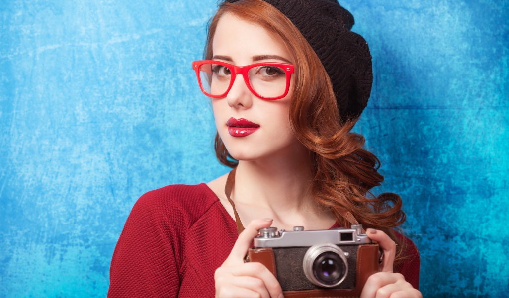 Красивая рыжеволосая девушка в черном берете с фотоаппаратом в руках 