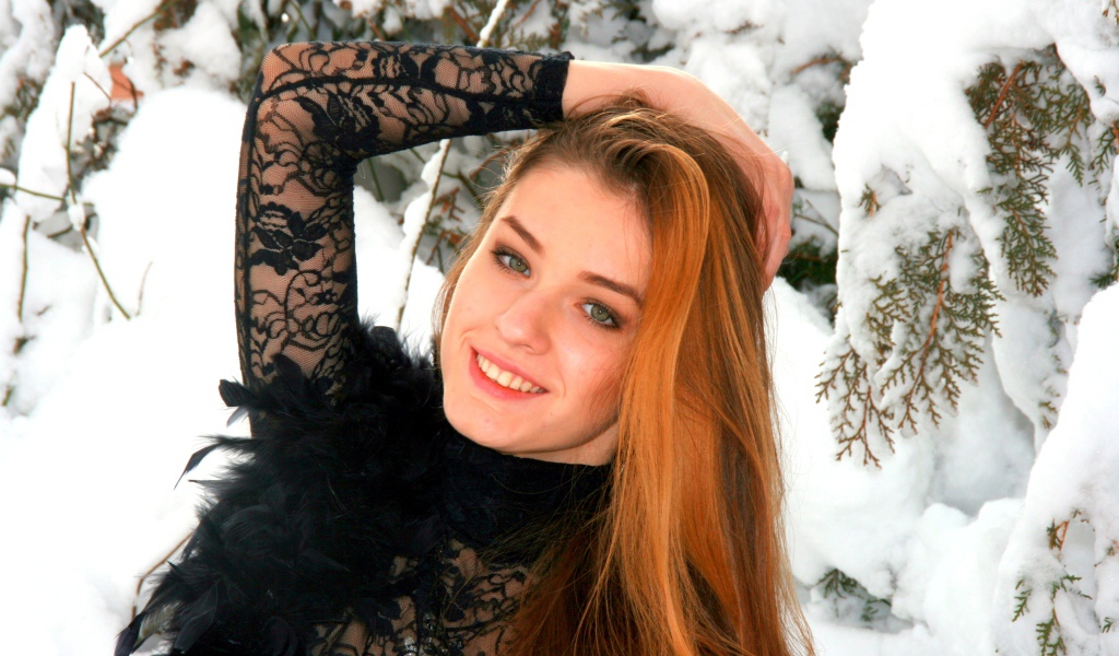 Красивая рыжеволосая девушка у заснеженной туи