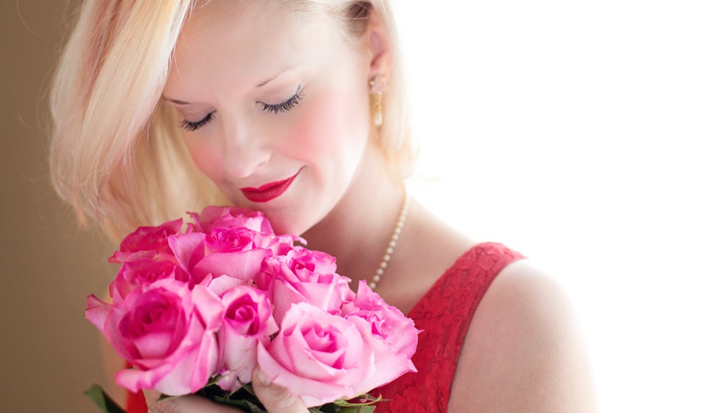 Блондинка с закрытыми глазами нюхает букет роз