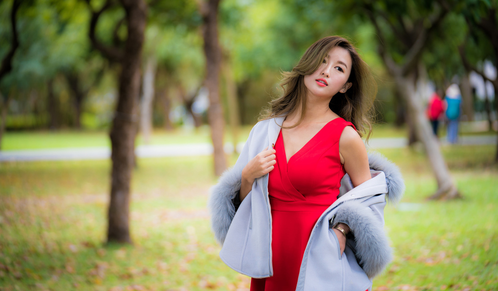Bright Asian girl in a red dress in the park