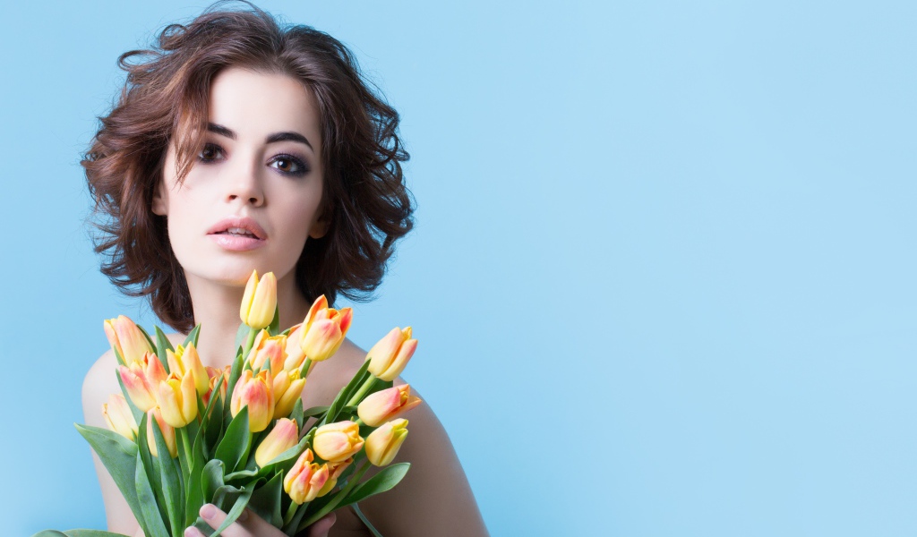 Кареглазая шатенка с букетом тюльпанов на голубом фоне
