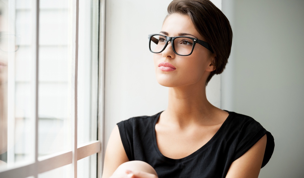 Деловая девушка в очках сидит у окна 