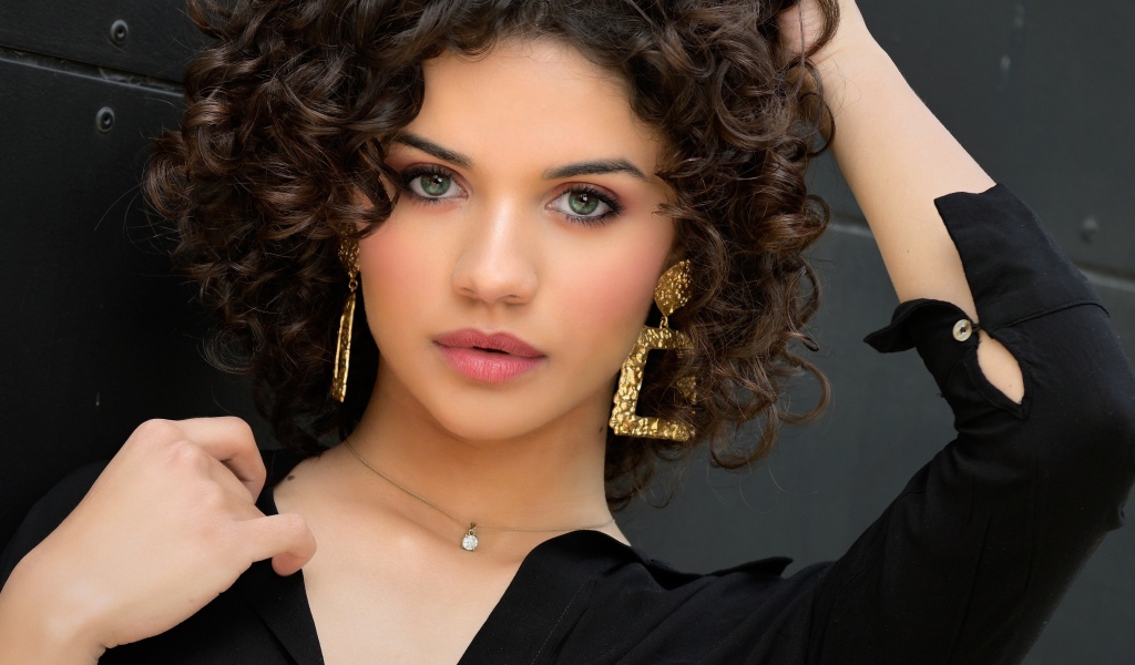 Кудрявая девушка с рукой в волосах в черной рубашке 