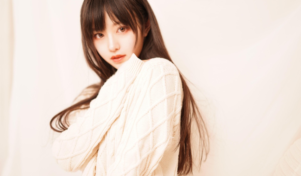 Милая азиатка в белом свитере на розовом фоне