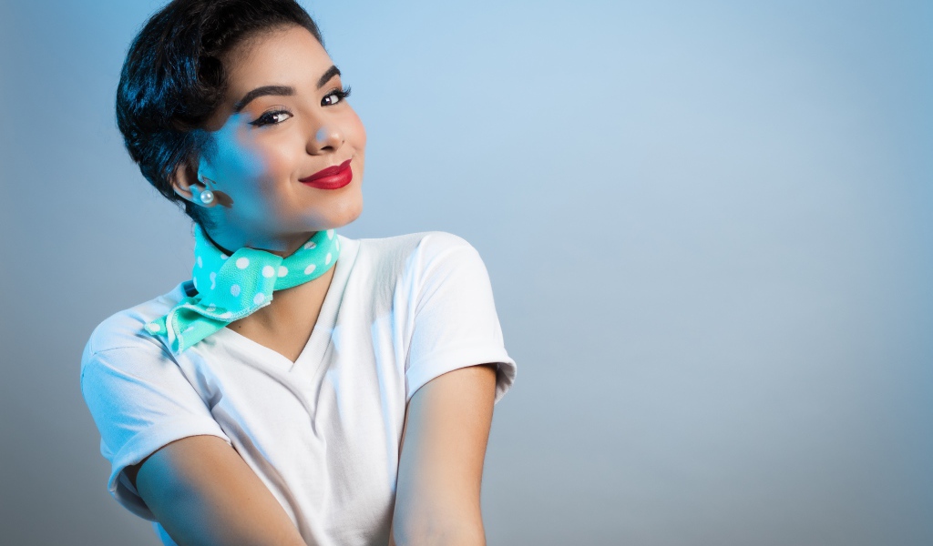 Милая улыбающаяся девушка с шарфом на шее на сером фоне