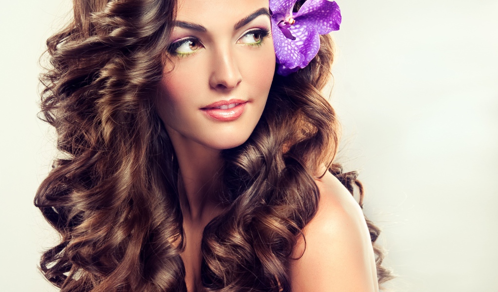 Цветок в красивых длинных волосах молодой девушки