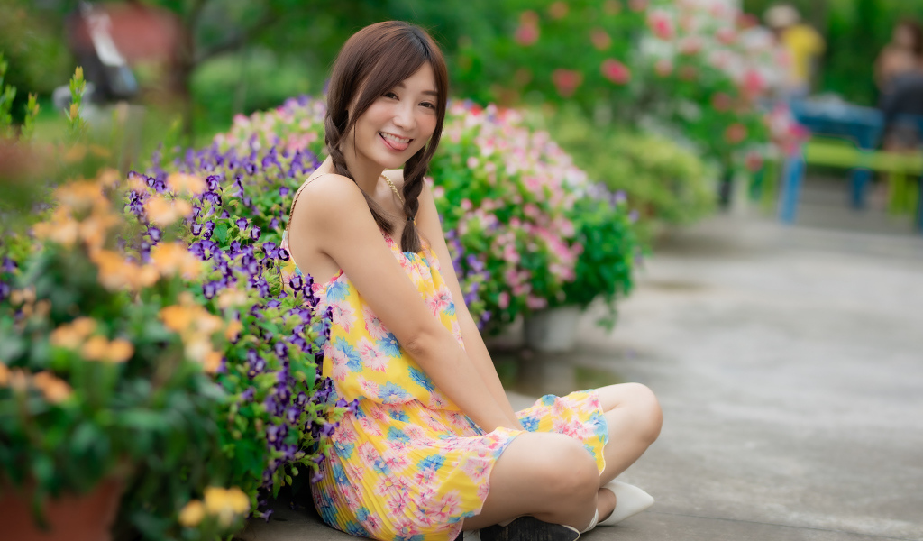 Смешная девушка азиатка в платье сидит на земле