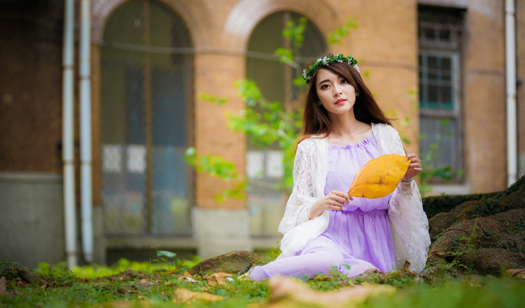 Девушка в красивом платье сидит на траве 