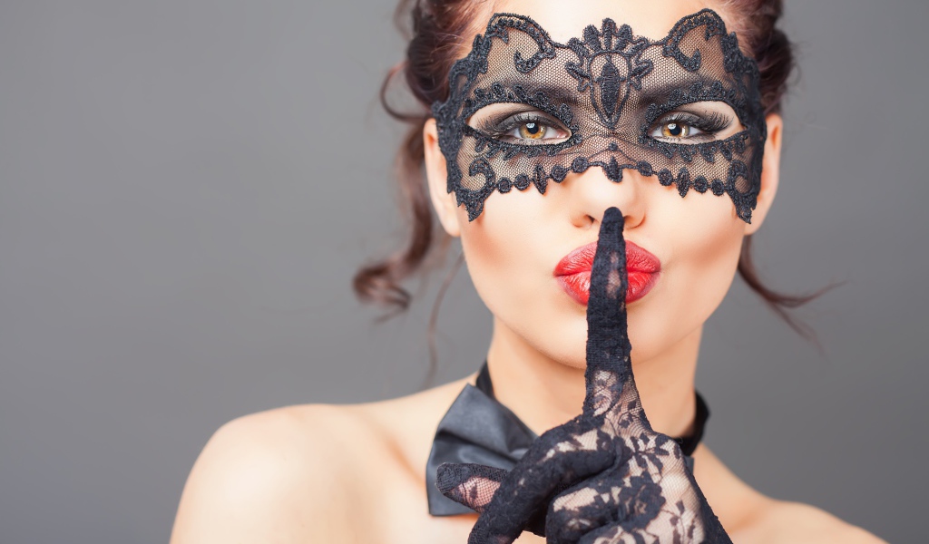 Девушка в черной маске с рукой в перчатке у лица