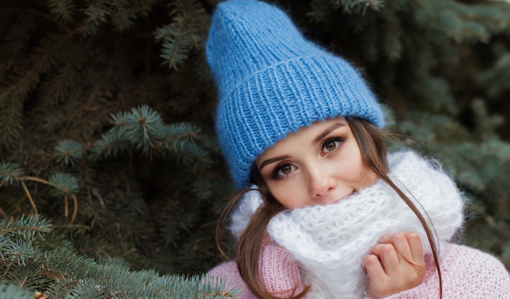 Девушка в голубой вязаной шапке у ели