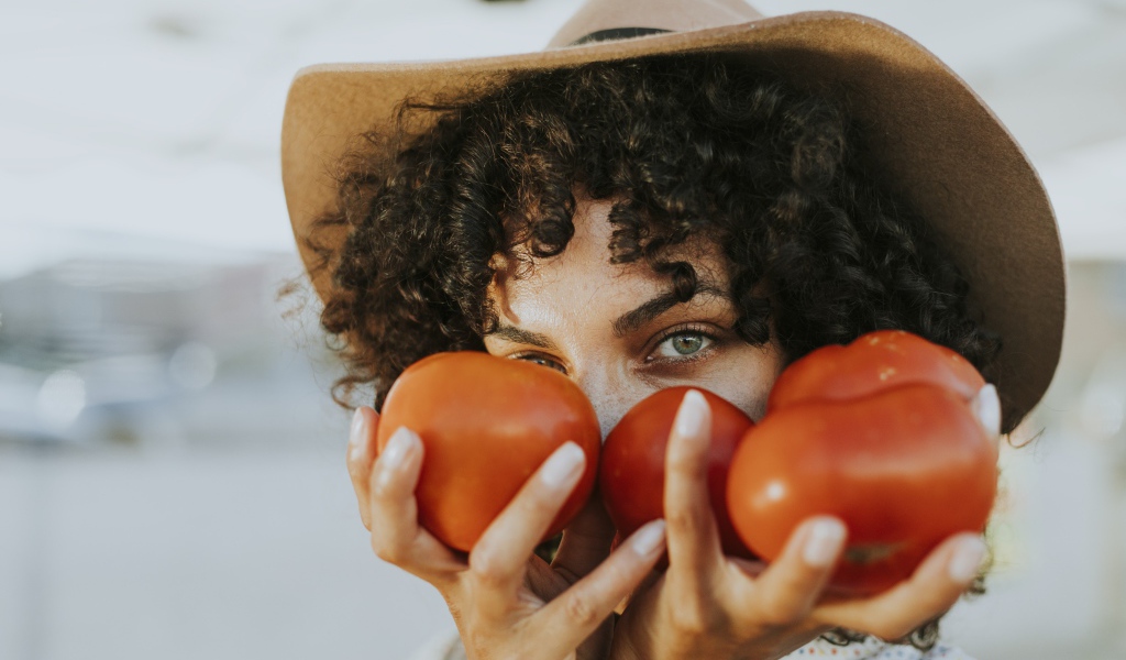 Девушка в шляпе с помидорами в руках 