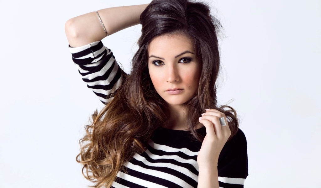 Девушка в полосатом свитере с рукой в волосах на белом фоне